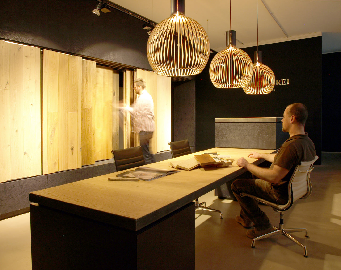 Besprechungsbereich im Parkett-Showroom mit hochwertigen Holzmustern und moderner Beleuchtung, ideal für Gewerbekunden und Architekten.