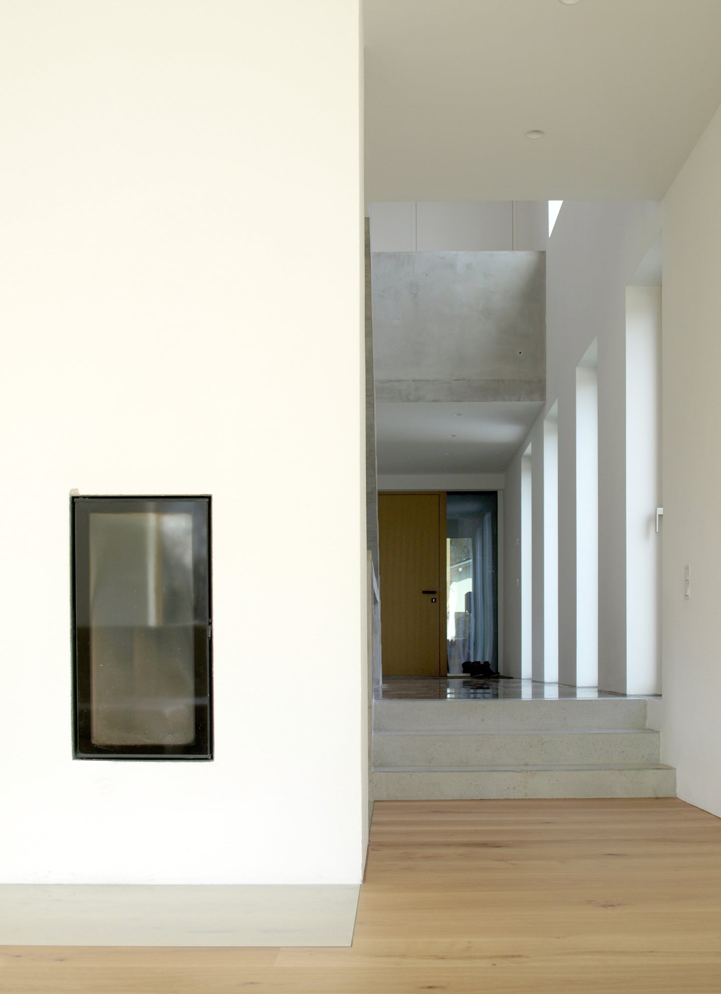 Offener Flur mit Blick auf einen modernen Kamin, umgeben von klaren Linien und natürlichem Lichteinfall.