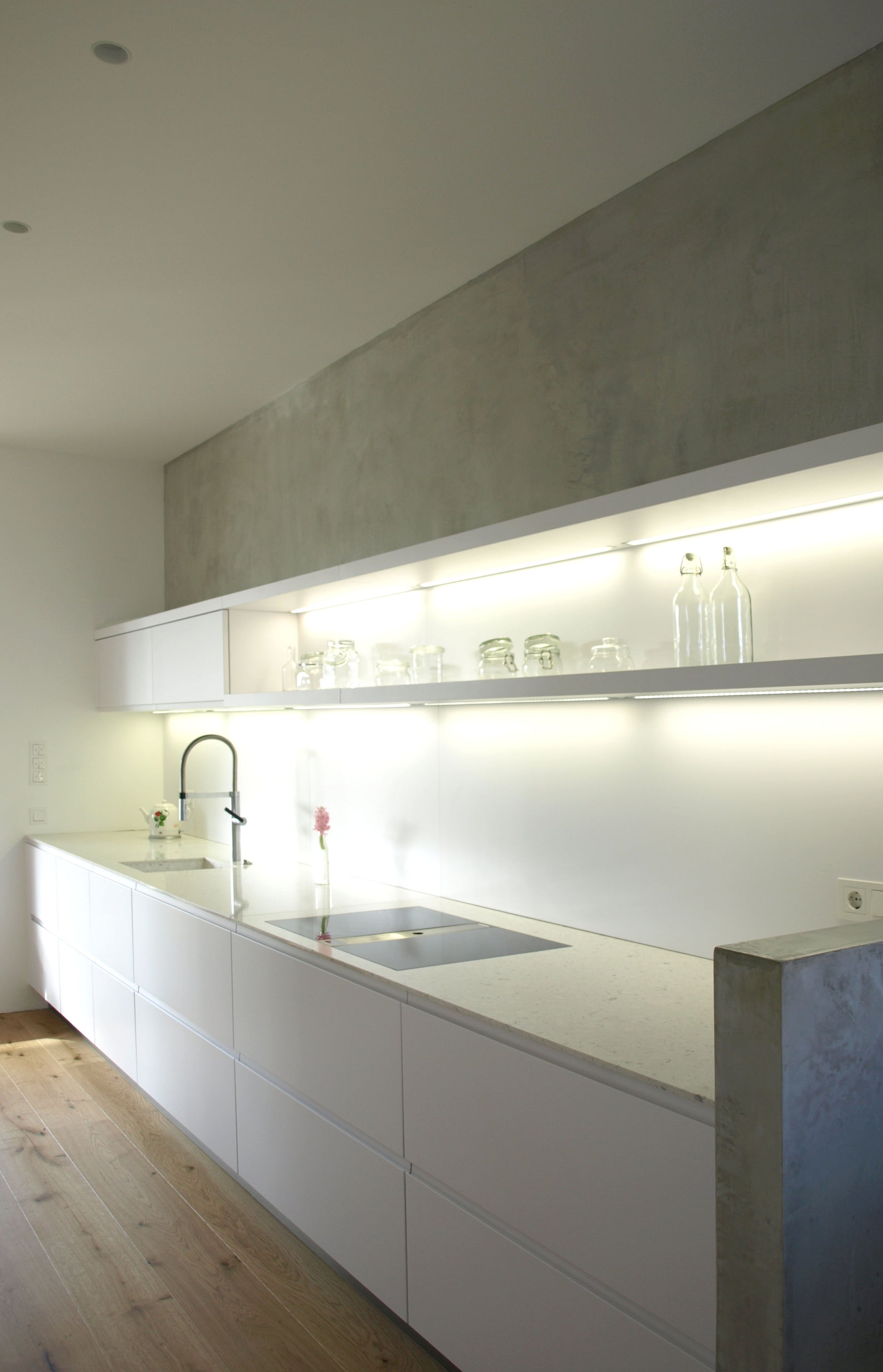 Moderne Küche mit integriertem Lichtsystem und minimalistischer Gestaltung, eingebettet in einem Einfamilienhaus mit zeitgemäßer Architektur.