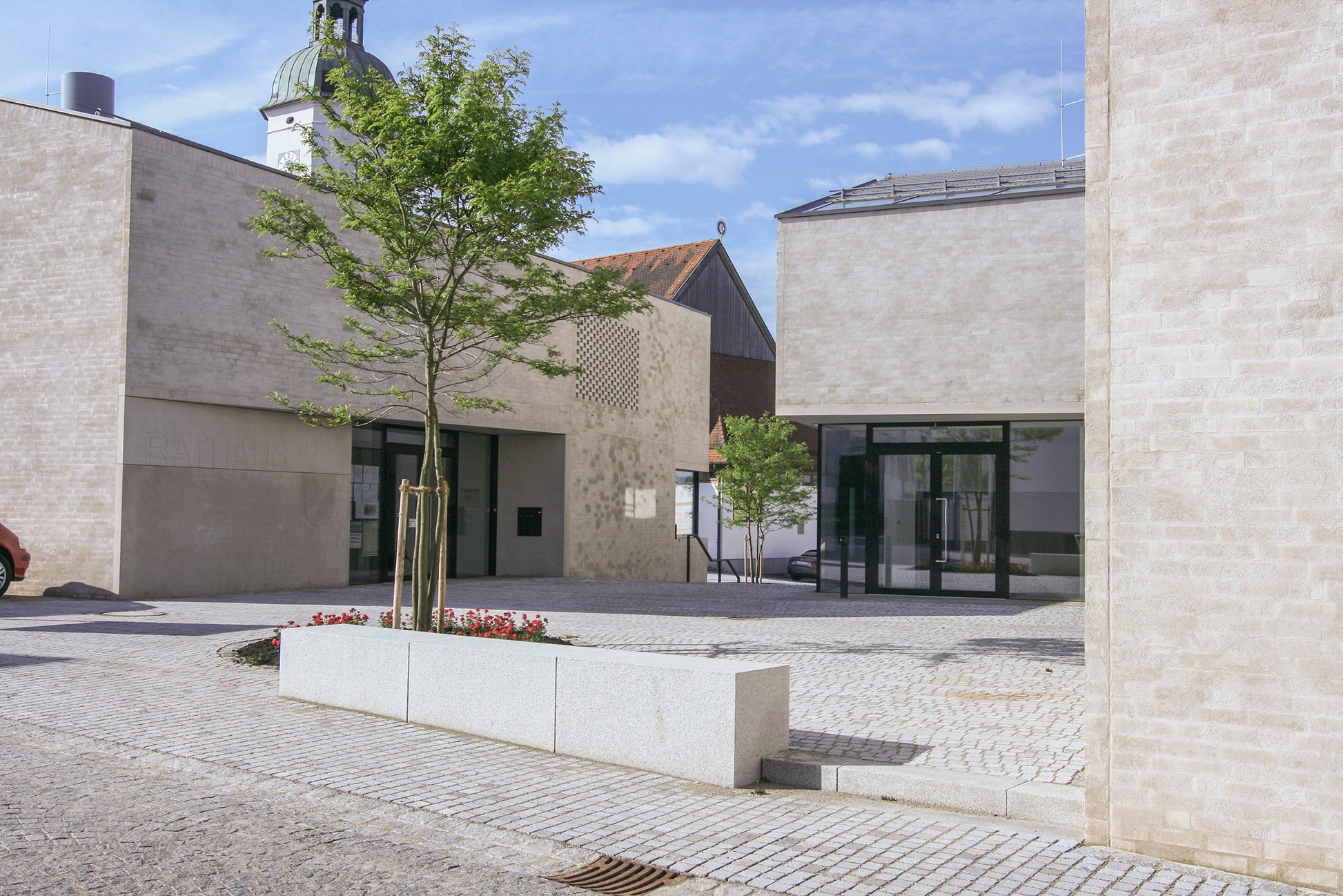Ansicht des neuen Rathausplatzes in Wettstetten mit moderner Architektur und Platzgestaltung in unmittelbarer Nähe zur Kirche St. Martin.