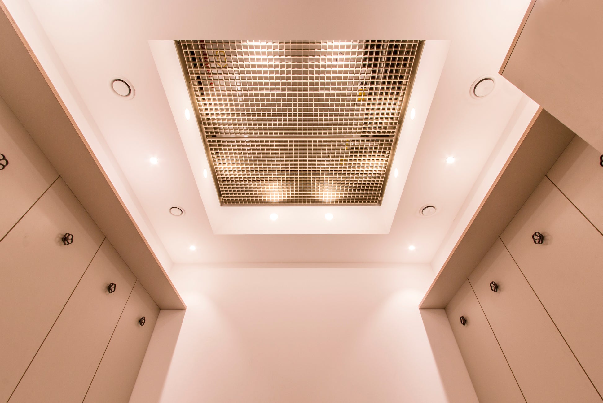 Modernes Deckendesign mit Lichtinstallation in einer hochwertigen Mitarbeiter-Duschanlage.
