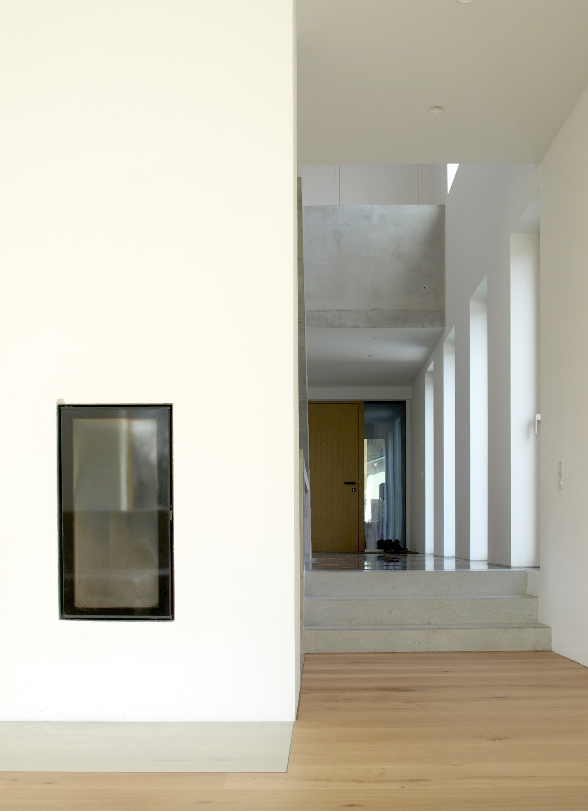 Offener Flur mit Blick auf einen modernen Kamin, umgeben von klaren Linien und natürlichem Lichteinfall.