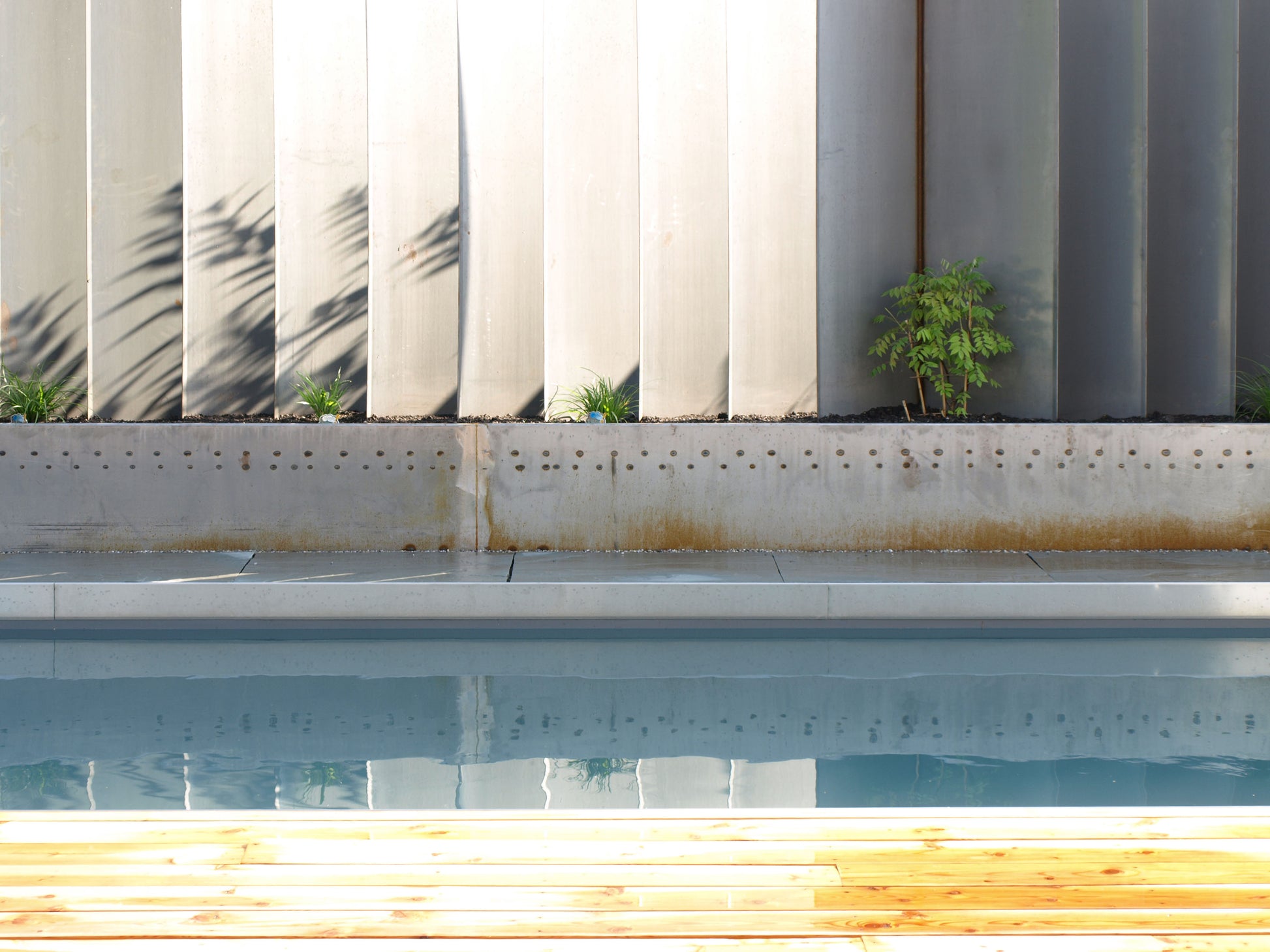 Detailaufnahme eines minimalistischen Pools mit angrenzender Holzterrasse, Teil eines zeitgenössischen Wohnkonzepts.