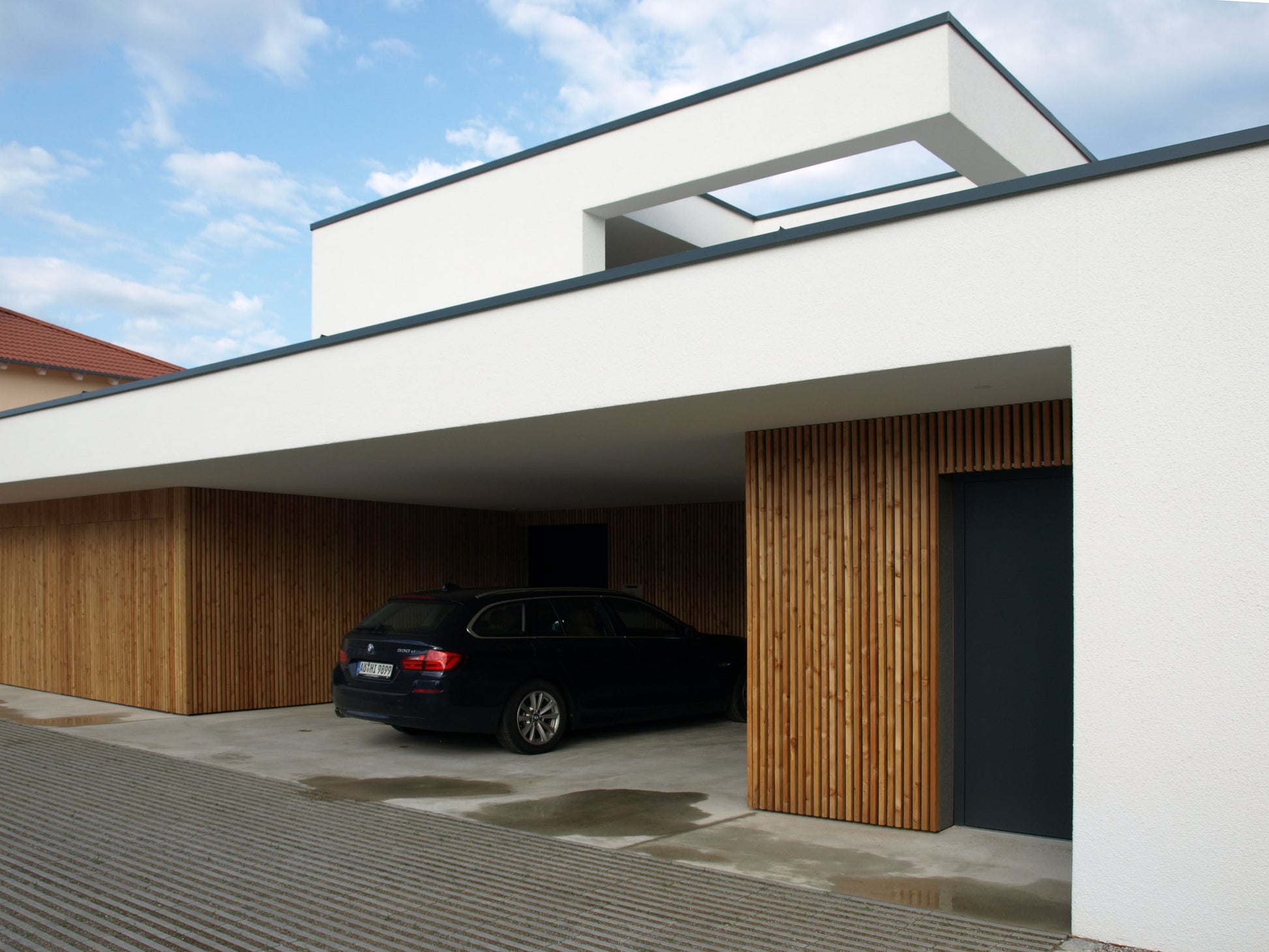 Einfamilienhaus mit überdachter Carport-Lösung und moderner Holz- und Putzfassade, gestaltet für hohe Funktionalität.