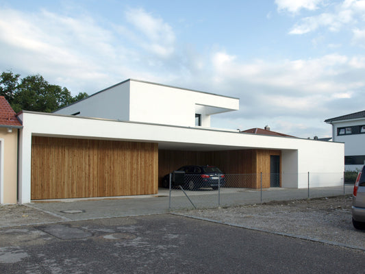 Panorama eines modernen Wohnhauses mit klaren Linien und weiten Überhängen, akzentuiert durch natürliche Materialien.