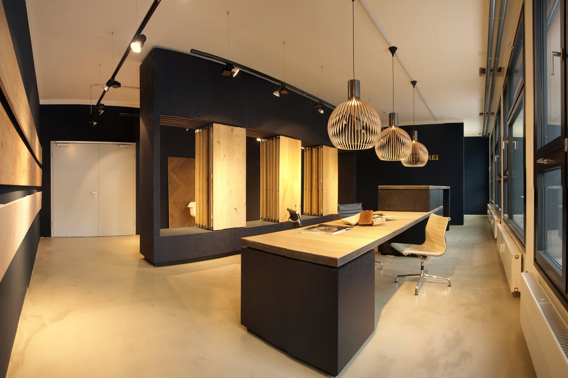 Panoramaaufnahme eines modernen Parkett-Showrooms mit maßgefertigten Präsentationsmöbeln, minimalistischer Raumgestaltung und natürlichen Materialien.